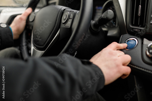 driver pushing car engine start-stop button in modern car. © VAKSMANV