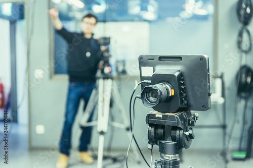 Fototapeta Naklejka Na Ścianę i Meble -  Film camera in broadcasting studio, spotlights and other equipment, cameraman in the blurry background
