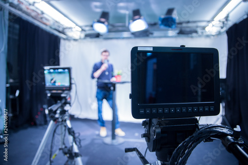 Journalist in a television studio is talking into a microphone  blurry film cameras
