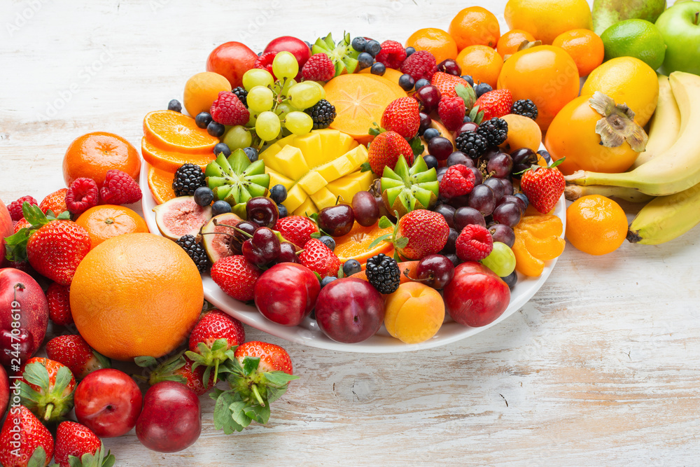 Naklejka Healthy platter with colorful rainbow fruits, strawberries raspberries oranges plums apples kiwis grapes blueberries mango persimmon, copy space, selective focus