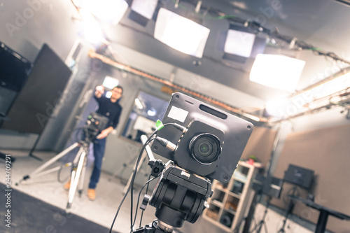 Film camera in broadcasting studio, spotlights and equipment, cameraman in the blurry background