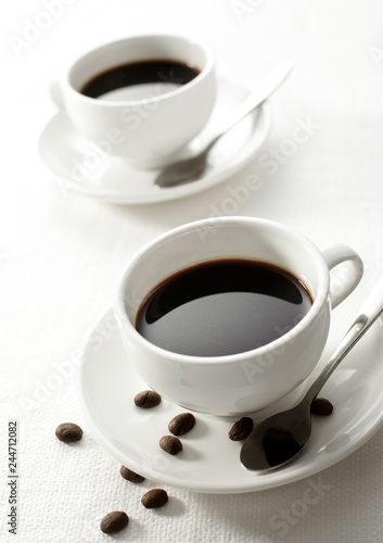 Two cups white tablecloth, with a little coffee beans