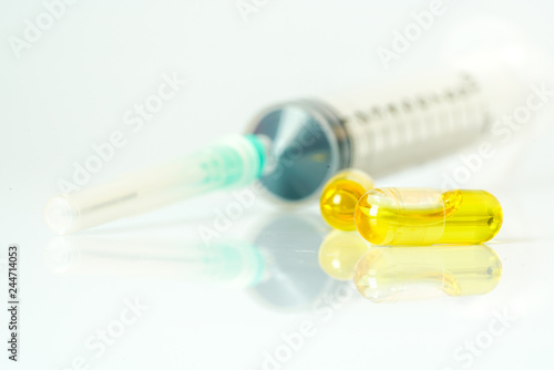 Olive capsules and syringe with white background.
