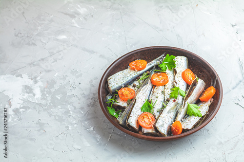 Sardines or baltic herring with rosemary, thyme, parsley,  tomatoes slices and spaces
