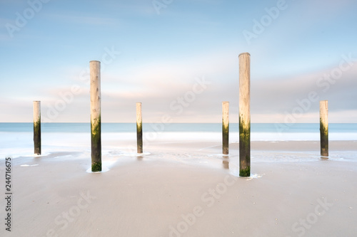 Poles on a beach with blue sky long exposure landscape
