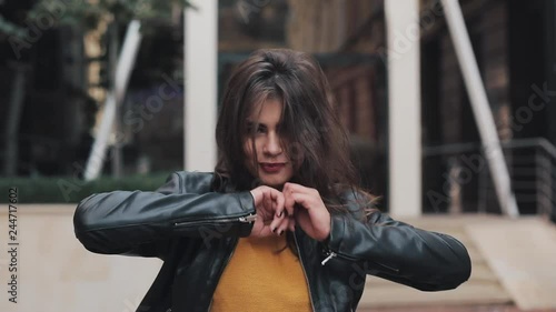 Happy young woman walking on the street, looking and posing into the camera. Beautiful girl moving in dance. Slow motion photo