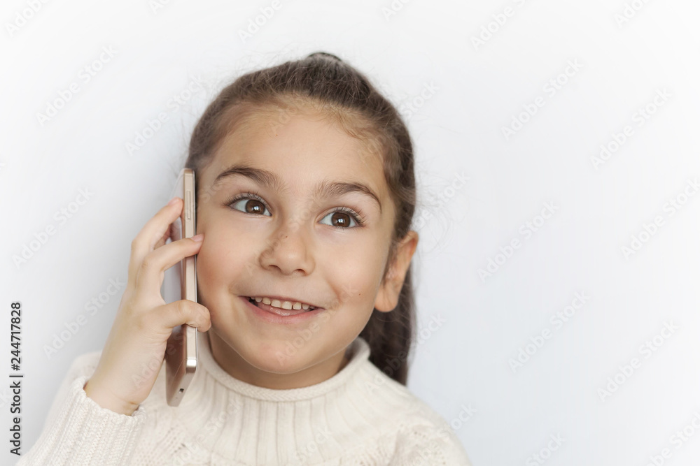 Portrait of a smiling cute child girl holding smartphone over white background. Happy child face. Technology