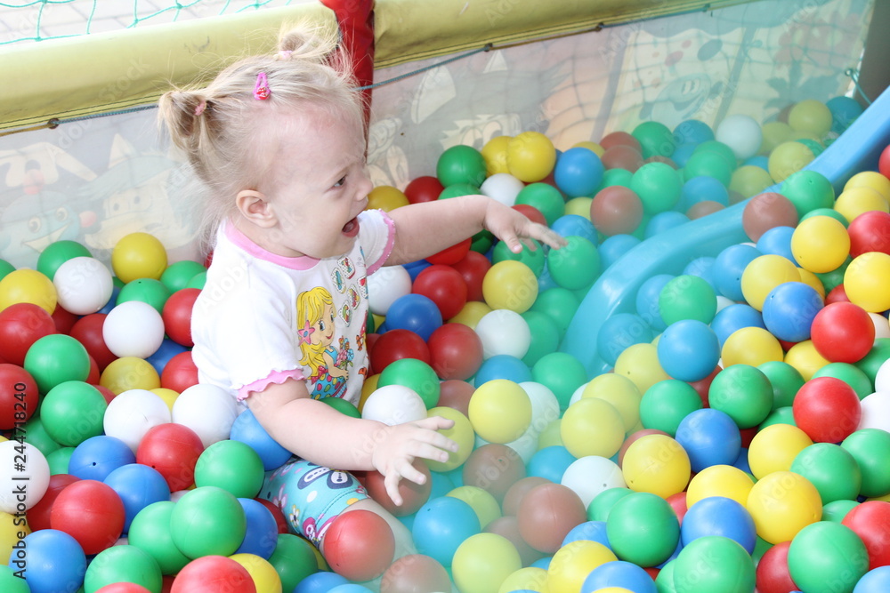 Mothers with babies plays in dry swimming pool and sits on the colored plastic balls. Mothers with babies plays in dry swimming pool and sits on the colored plastic balls.