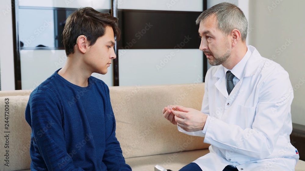 Obraz premium A doctor shows a hearing aid to a hearing impaired guy.