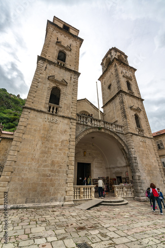 KOTOR, MONTENEGRO - JULY 12, 2014: The Main Square boasts many street cafes, tiny shops, scenic Kampana tower and the view on the foggy mountains on the background photo