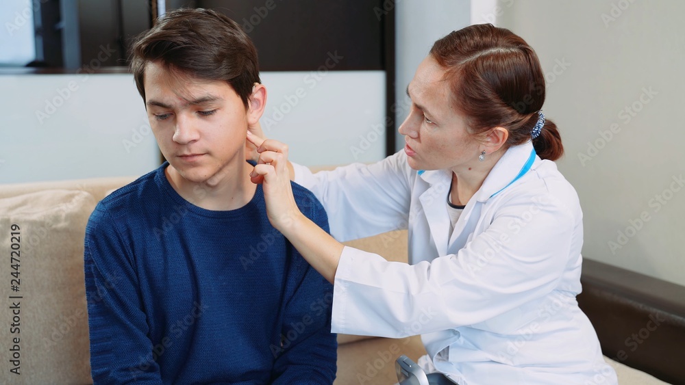 Woman doctor puts a hearing aid on a young guy. Woman doctor puts a hearing aid on a young guy.