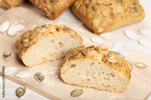 Baked bread with pumpkin seeds on cutting board. Wooden table, rustic style