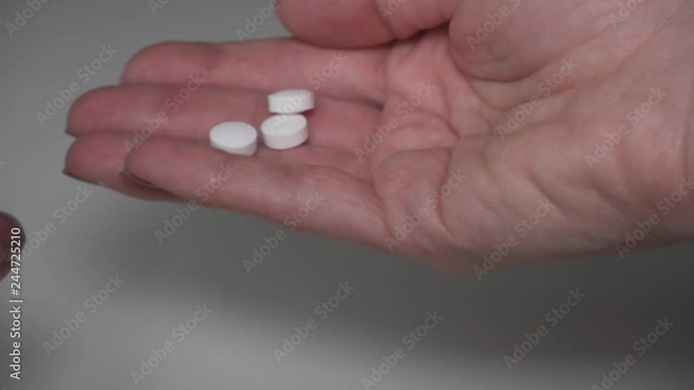 Taking three white pills from the jar. Pills being taken out from the bottle into the hand Taking three white pills from the jar. Pills being taken out from the bottle into the hand