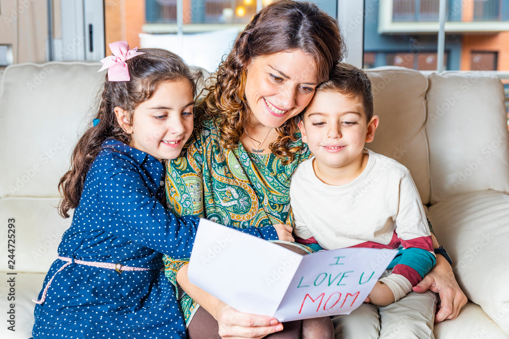Mother and children reading a greeting card on Mother's Day Mother and children reading a greeting card on Mother's Day