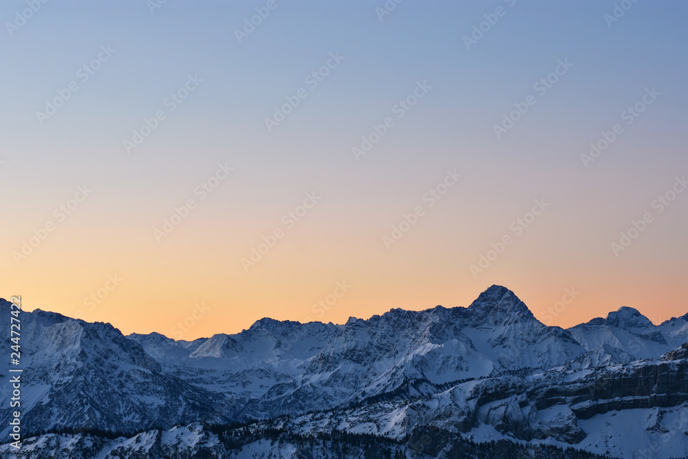 Colorful morning mood just before sunrise. View to the Allgaeu Alps with Widderstein mountain at a cold winter day. Copy space