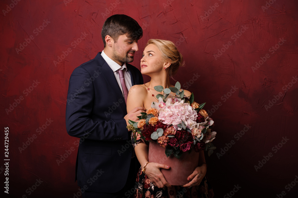 Young man hug his woman with the bouquet of flowers and looking in her eyes Young man hug his woman with the bouquet of flowers and looking in her eyes