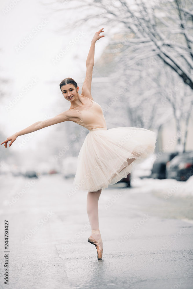 Obraz premium Beautiful ballerina is dancing on street of snowy city.