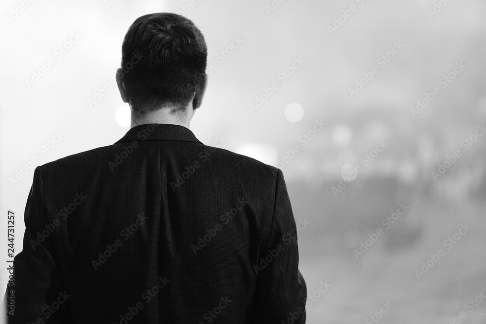 Young man in jacket photographed from the behind. Black&white photo.