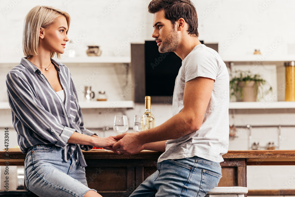 Fototapeta premium attractive girlfriend and handsome boyfriend holding hands and talking