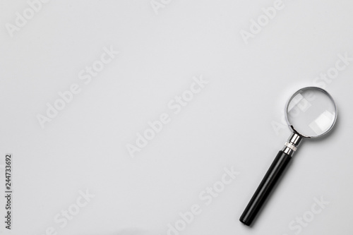 Magnifying glass on color paper background top view