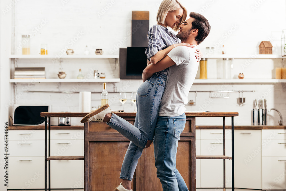 handsome boyfriend and attractive girlfriend hugging and standing in kitchen handsome boyfriend and attractive girlfriend hugging and standing in kitchen