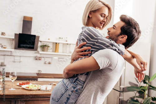 handsome boyfriend and attractive girlfriend hugging and smiling in kitchen © LIGHTFIELD STUDIOS