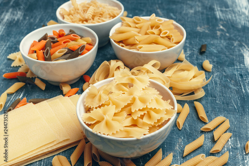 Different pasta types in bowls on the table.