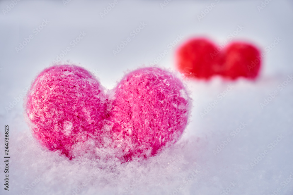 Fototapeta premium Two wool red and pink hearts standing on the white fluffy snow