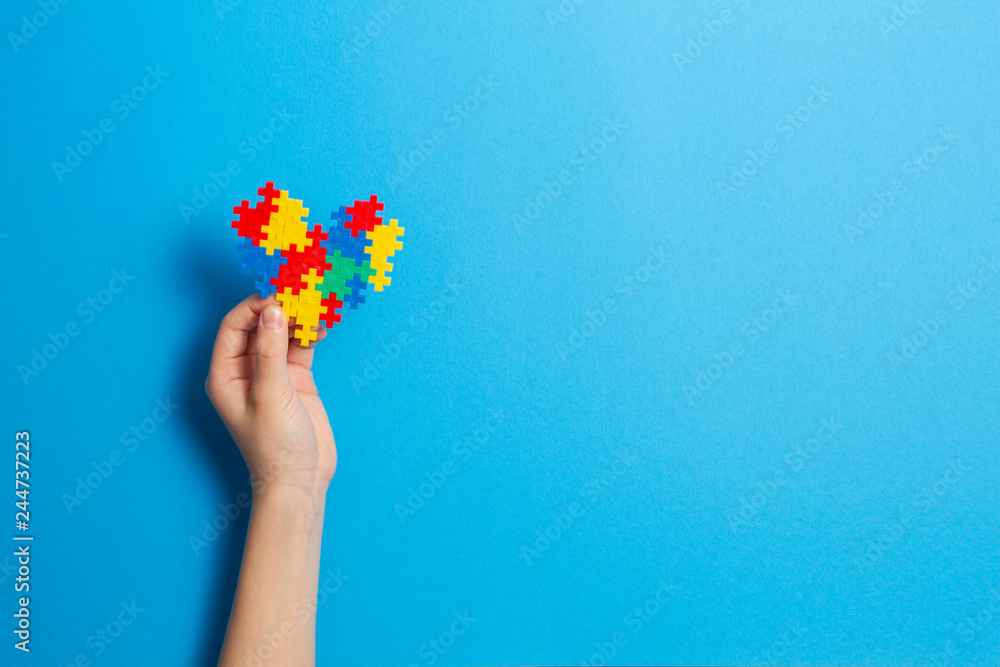 Child hand holding colorful heart on blue background. World Autism Awareness Day, Autism Acceptance Month, neurodiversity concept Child hand holding colorful heart on blue background. World Autism Awareness Day, Autism Acceptance Month, neurodiversity concept