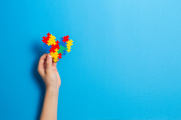 Child hand holding colorful heart on blue background. World Autism Awareness Day, Autism Acceptance Month, neurodiversity concept