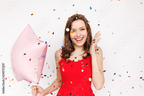 Excited woman with balloon under confetti