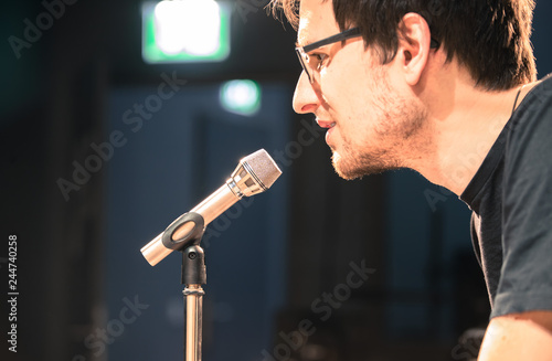 Speaker on the stage: Young Caucasian man is talking into a mirophone photo