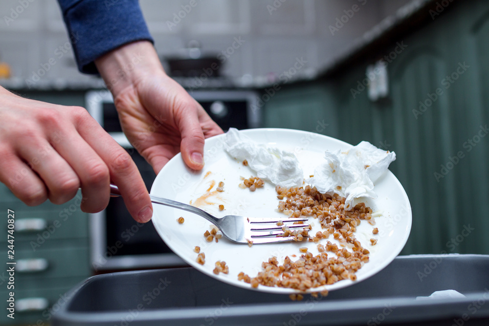 Close up of a person throwing from a plate the leftover of buckwheat to