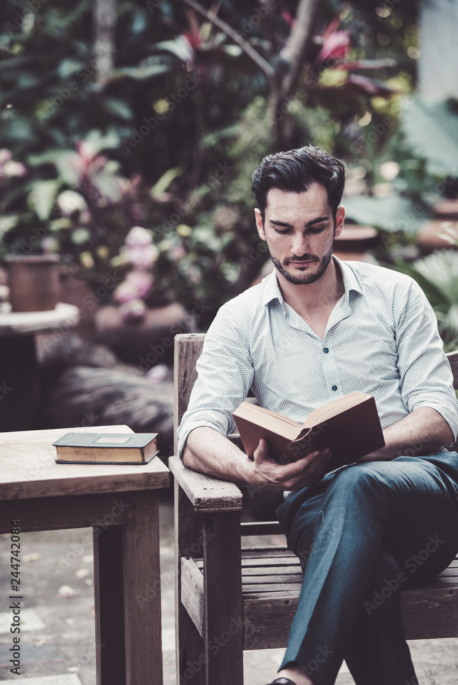 Fototapeta premium man reading a book on a chair in the park, successful people read in the morning every day.