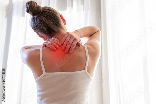 Fototapeta Young woman massaging her neck because of suffering from pain neck, stretching the muscles