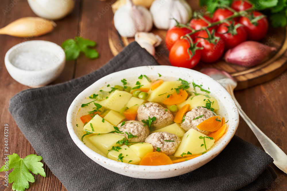 meatballs soup in white plate on old wooden rustic brown table, side view meatballs soup in white plate on old wooden rustic brown table, side view