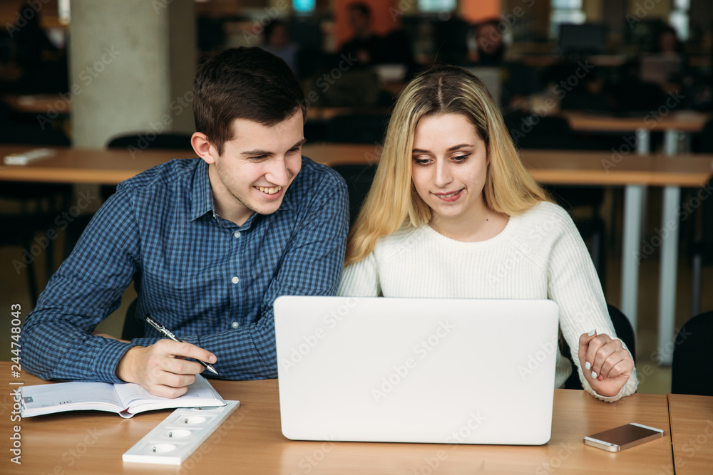 Boy and girl sits in universiti library. They use laptop to prepare for an exam. Study Boy and girl sits in universiti library. They use laptop to prepare for an exam. Study