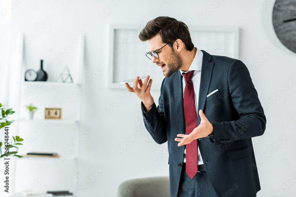 angry businessman in formal wear yelling at smartphone during conversation in office angry businessman in formal wear yelling at smartphone during conversation in office