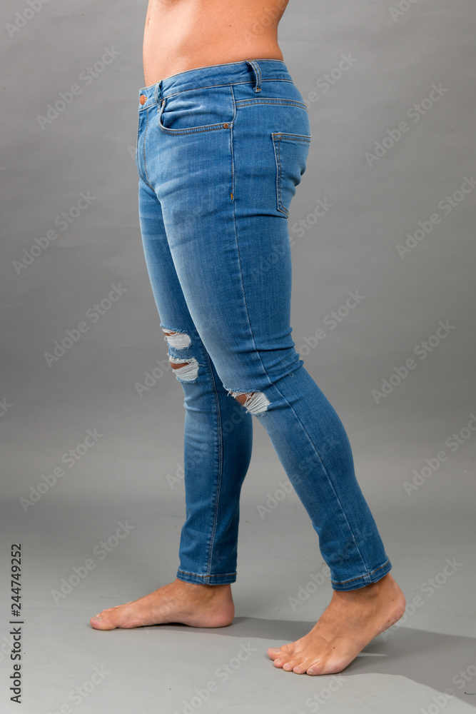 Modern male unbranded Blue skinny ripped jeans isloated on grey background