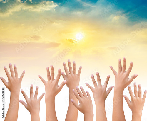 kids Raising hands up together on sunset sky background
