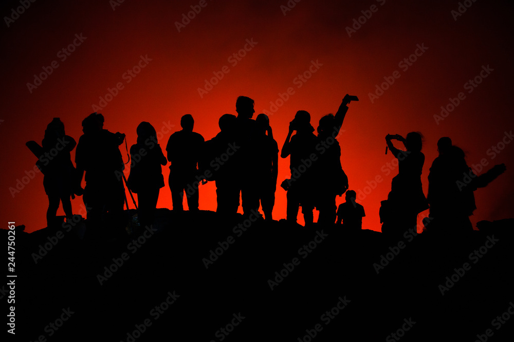 Unrecognized Tourists's silhouettes on Erta Ale Volcano edge illuminated with lava. Danakil Depression, Ethiopia, East Africa Unrecognized Tourists's silhouettes on Erta Ale Volcano edge illuminated with lava. Danakil Depression, Ethiopia, East Africa