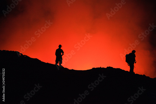 Unrecognized Tourists's silhouettes on Erta Ale Volcano edge illuminated with lava. Danakil Depression, Ethiopia, East Africa