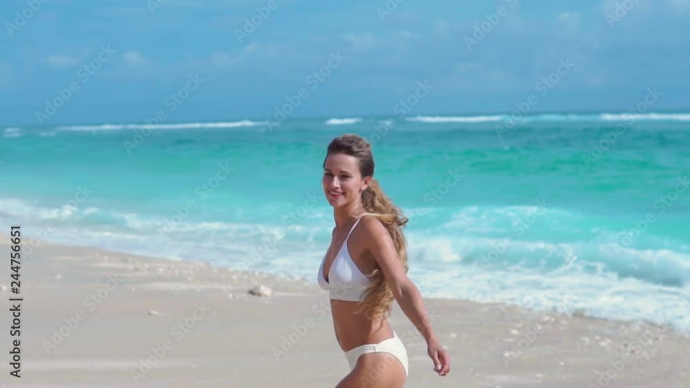 Portrait of pretty beautiful sport fashion woman in white bikini posing in summer near the sea and blue sky in sunshine with gorgeous smile in happy mood on tropic island on vacation Portrait of pretty beautiful sport fashion woman in white bikini posing in summer near the sea and blue sky in sunshine with gorgeous smile in happy mood on tropic island on vacation