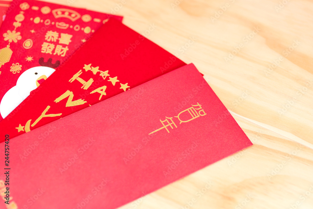 Red envelope packet chinese new year, hongbao with the character 'Happy New Year' on wood background for Chinese New Year. Translation: Good luck in the year Red envelope packet chinese new year, hongbao with the character 'Happy New Year' on wood background for Chinese New Year. Translation: Good luck in the year