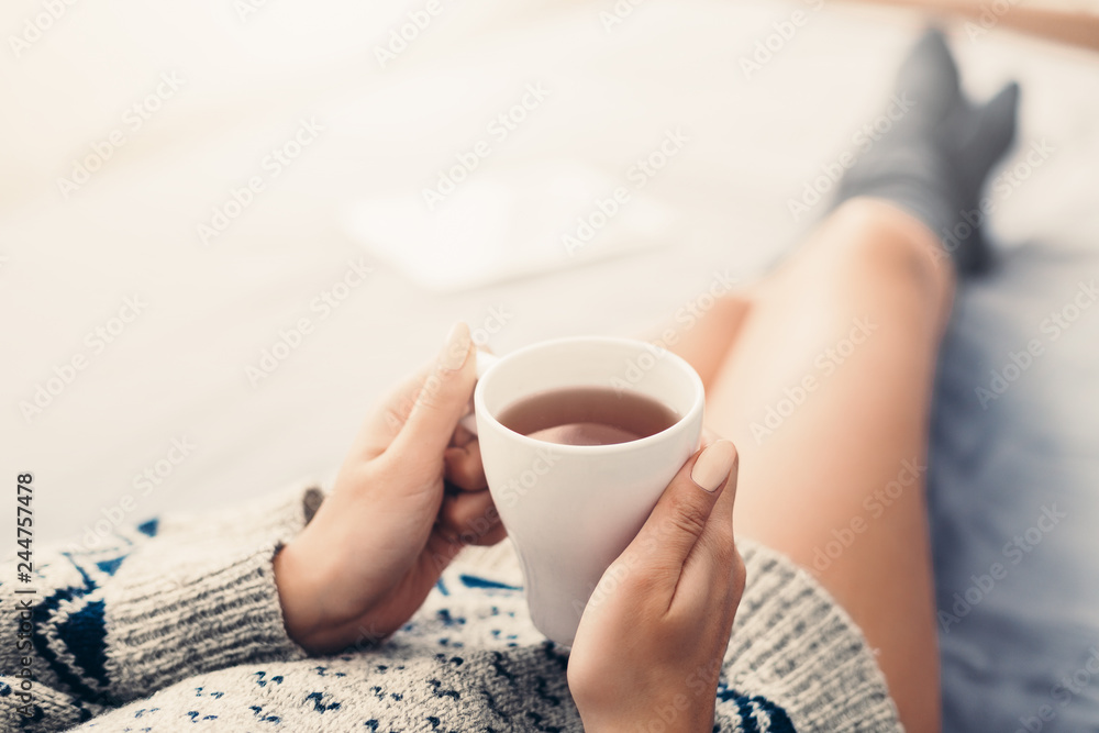 Woman resting in bed with cup of tea