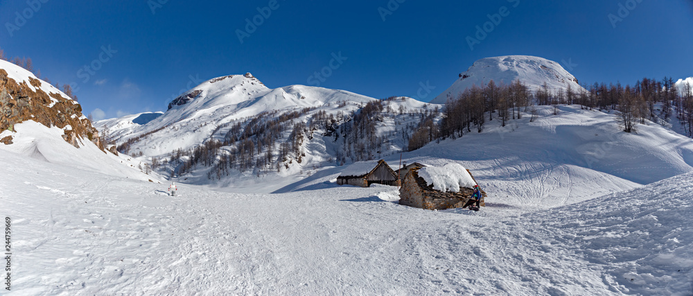 Some hikers in the sunny snowy landscape of the Alpe Sangiatto above Alpe Devero in Piedmont, Italy.