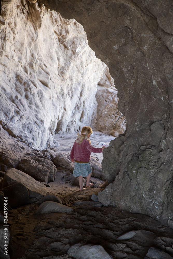 Young girl playing in a cave at a beach in California. Young girl playing in a cave at a beach in California.