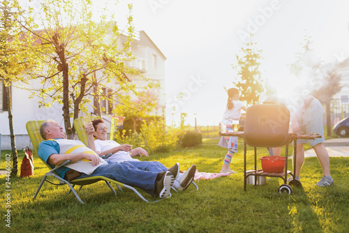 Picture of older couple lying down in chairs in their backyard and enjoining after good barbeque