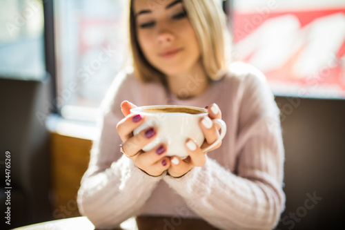 Young Woman holding cup drinking coffee in a cafe