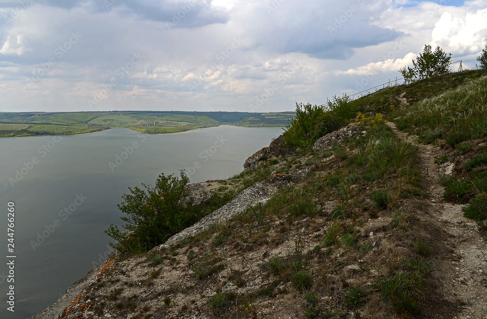 Huge sheer stone cliffs on the background of a river Dniester and a blue sky with clouds